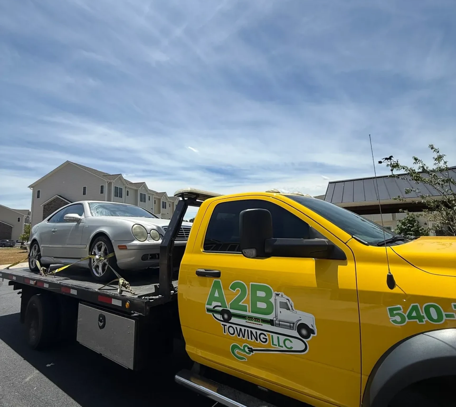 Silver car on a yellow tow truck