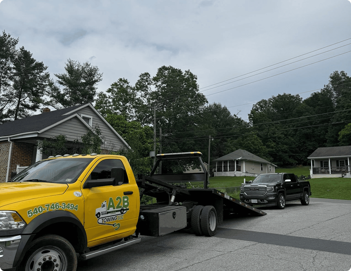 Yellow tow truck loading black vehicle roadside.