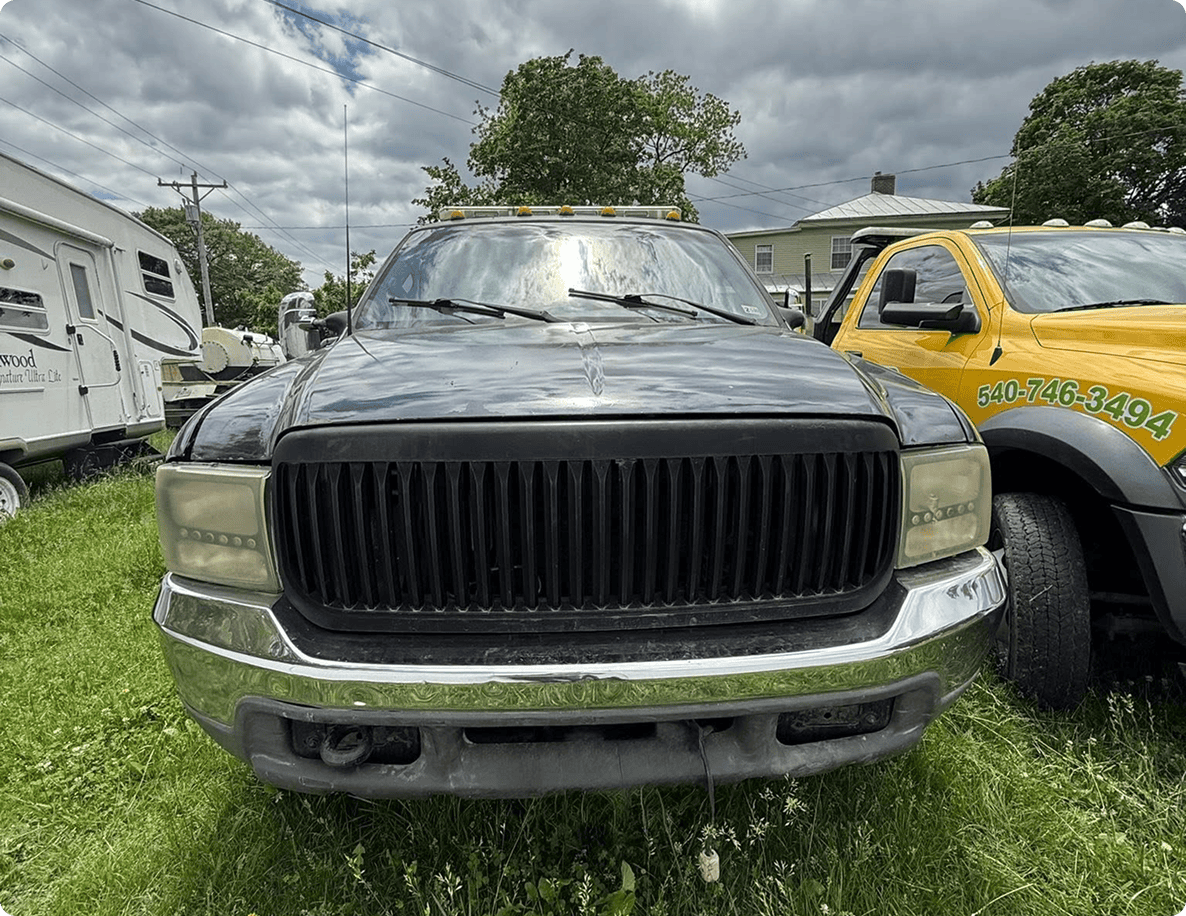 Black truck parked on grassy field.