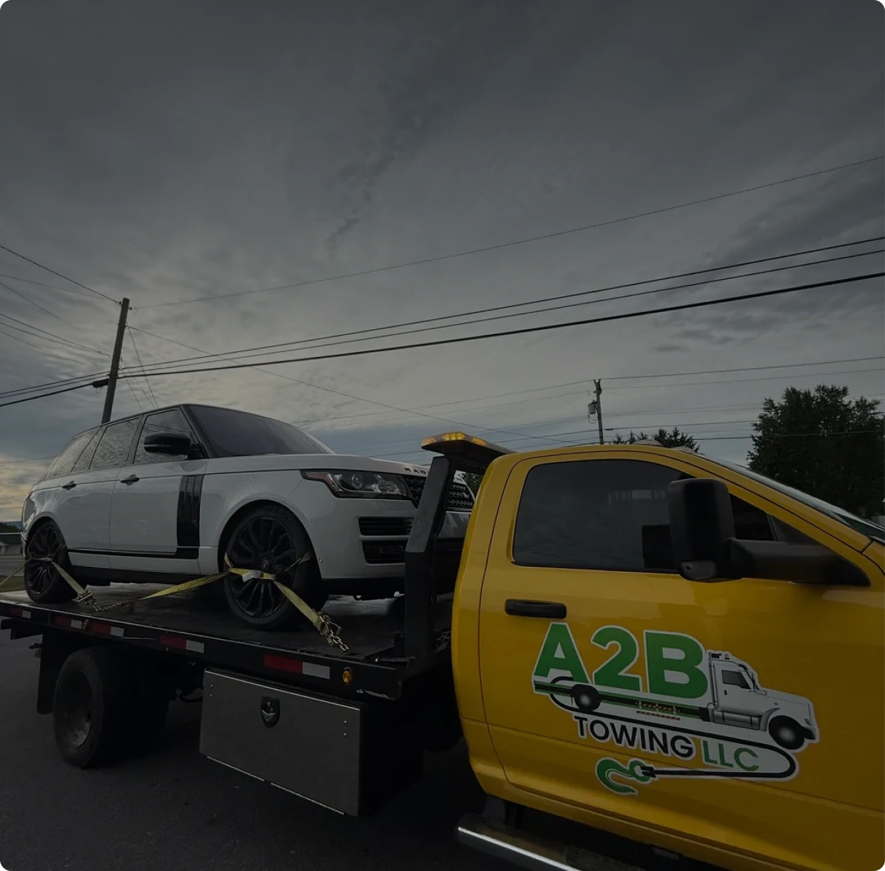 Tow truck transporting white SUV on road.